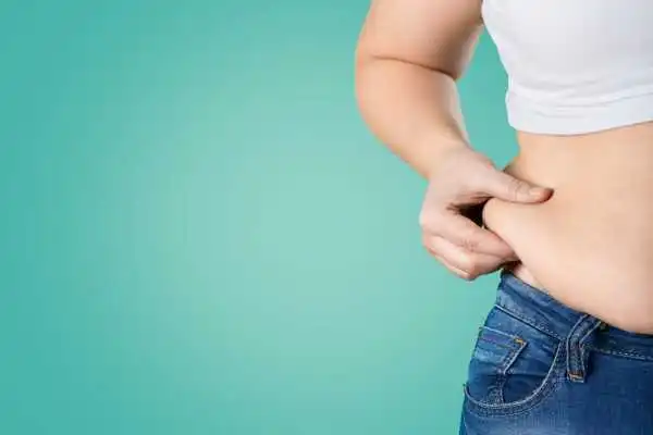 Image of woman pinching her love handles to show weight gain Warrington
